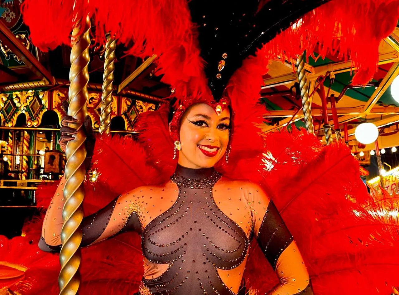 Vegas showgirl in a red feather headdress posing on a fairground carousel
